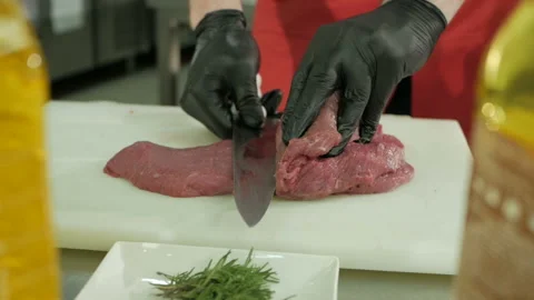 The chef cuts the raw beef with a knife in black gloves. Slow motion Stock-Footage 106256693