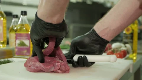 The chef cuts the raw beef with a knife in black gloves. Slow motion Stock-Footage 106258308