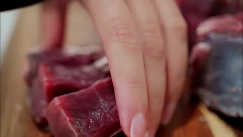 Chef cuts raw beef steak into cubes on wooden cutting board for cooking del.. Stock Footage 339202943