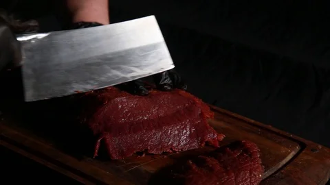 Chef cuts raw meat with big knife on a wooden board in the dark Stock Footage 124720087