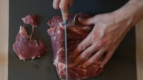 The chef cuts raw meat with the knife. Chef cutting pork meat. Cutting meat Stock Footage 99880625
