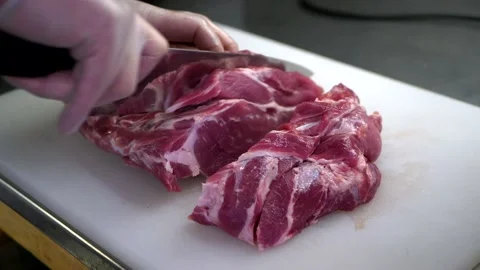 Chef cuts raw meat with the knife on white board. Video stock 151927086