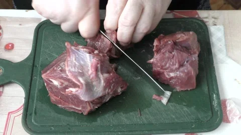 Chef cuts raw meat with a knife Stock Footage 173568428
