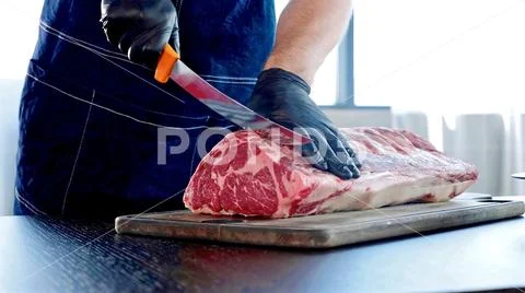 Chef cuts raw meat on the wood board with the knife, close-up Stock Photos