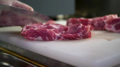 Chef cuts raw pork meat with a knife close-up on a white cutting board Stock Footage 150977311
