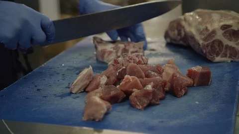 The chef cuts raw red meat pork in pieces with the knife in Slow Motion Stock Footage 119491477