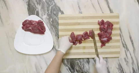 Chef cuts raw red meat into pieces on a wooden cutting board Stock Footage 154219613