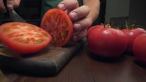 Chef cuts ripe red tomato in a half on the wooden board Video stock 143777304