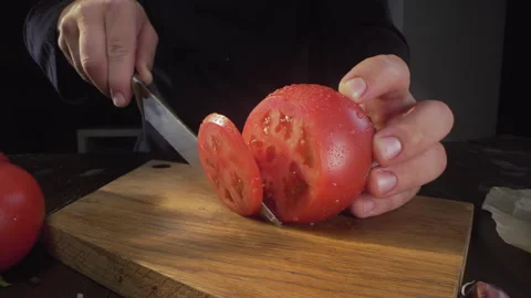 Chef cuts ripe red tomato in a circles on the wooden board Stock Footage 143777349