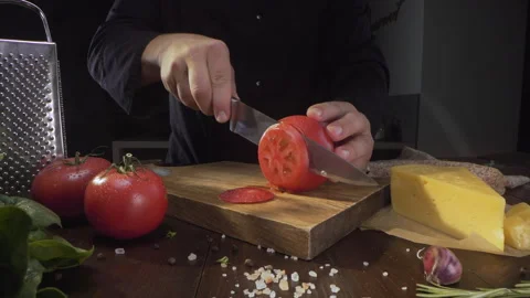 Chef cuts ripe red tomato in a circles on the wooden board Stock Footage 143777364