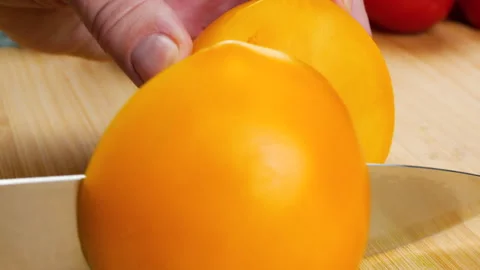 A chef cuts ripe yellow tomatoes on a wooden board. 库存影片 342282190