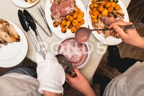 Chef cuts roasted meat for restaurant guests Stock Photos