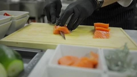 Chef Cuts Salmon on a Board With a Knife. The chef is cooking salmon. Chef is sl Stock Footage 220779181