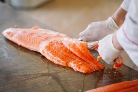The chef cuts the salmon on the table. Stock Photos