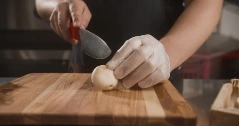 Chef cuts with sharp knife on wooden board onion into rings. Slow motion Stock Footage 113875935