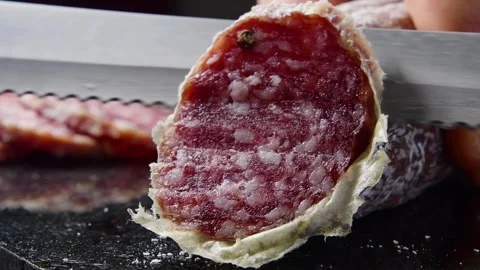 Chef cuts a slice of Italian salami on a granite cutting board Stock Footage 241493976