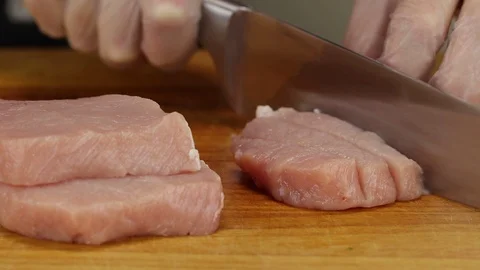 A chef cuts a slice of raw pork Stock Footage