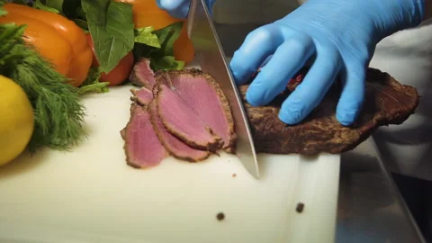 The chef cuts the smoked meat into thin slices Stock Footage 157981168