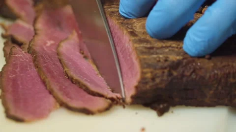 The chef cuts the smoked meat into thin slices Stock Footage 157981296