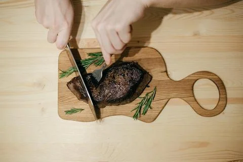 The chef cuts the steak with a large knife Stock Photos