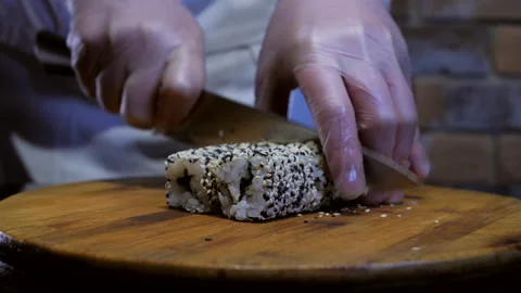 Chef cuts sushi maki with sharp knife into pieces. Traditional Japanese cuisine Stock Footage 132413794