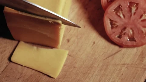 Chef cuts a thin piece of cheese with a sharp knife on a wooden cutting board Stock Footage 135880714