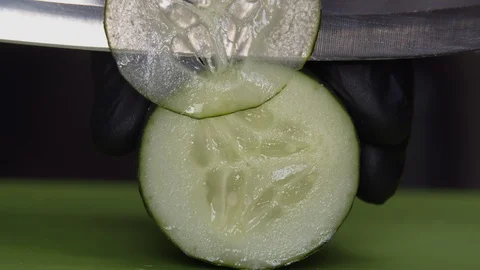 Chef cuts thin slices of fresh cucumber, macro shot Stock Footage 130018510