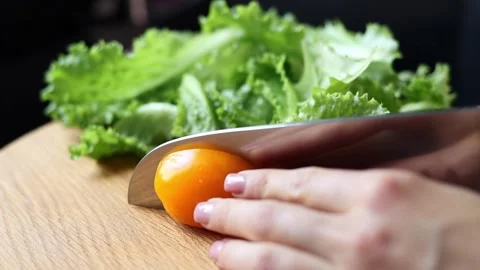 The Chef cuts a tomato in half on a wooden board on a black background Stock Footage 313282919