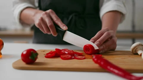 Chef cuts a tomato on the kitchen table, Slicing a tomato with a knife on a Stock Footage 323708893