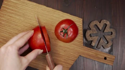 Chef cuts the tomato sharp steel knife on the wooden board Stock Footage 143777507