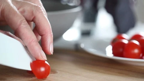 Chef cuts tomatoes by knife and puts them on a plate. Stock Footage 91729950