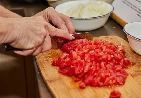 Chef cuts the tomatoes into small cubes for cooking Stock Photos