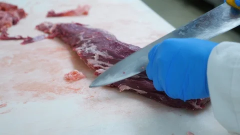 Chef cuts uncooked flank steak and removes gristle with the knife close up Video stock 104949970