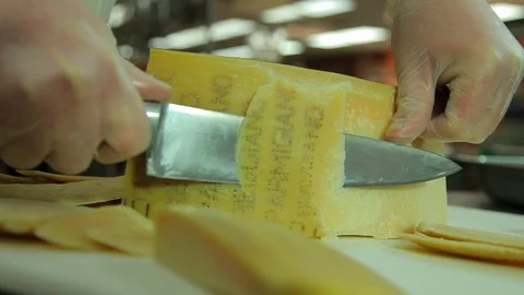 Chef. Cuts wheel of parmesan cheese in commercial kitchen. cu B Stock Footage 102184982