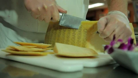 Chef. Cuts wheel of parmesan cheese in commercial kitchen. cu A Stock Footage 121805819