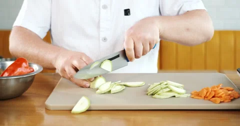Chef cuts zucchini at kitchen in restaurant. Working with knife, cooker prepares Stock Footage 133368053