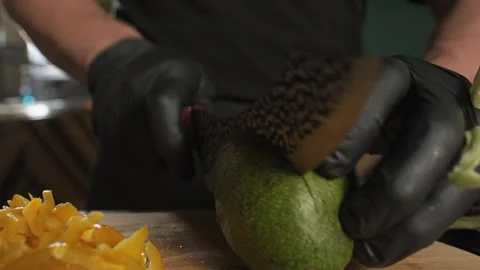 Chef cutting avocado with kitchen knife on cutting board Stock Footage 254480111