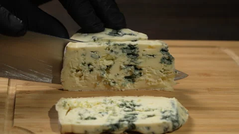 Chef cutting the blue cheese dorblu into slices with knife on wooden board Stock Footage 305433896