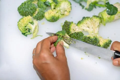 Chef cutting broccoli on a white cutting board. Stock Photos