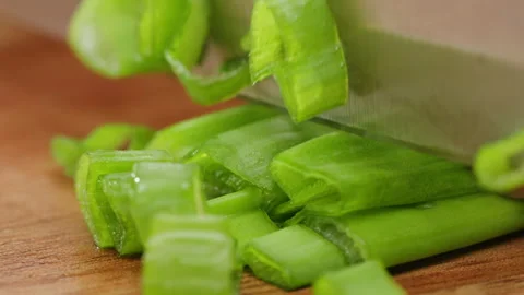 Chef cutting Bunch of green onion feathers by knife on a cutting board on Stock Footage 242528216