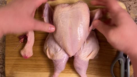 Chef cutting up a chicken carcass with a kitchen scissor on a cutting board. Stock Footage 307855059