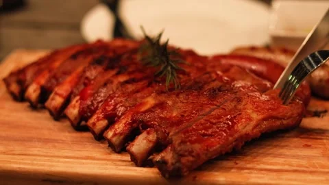 Chef cutting delicious slow cooked barbecue pork ribs on wooden board in ci.. Stock Footage 333697216