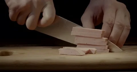 A chef is cutting doctor's sausage with a knife on a wooden chopping board 스톡 동영상 221122205