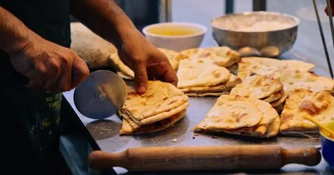 Chef cutting flatbread with pizza cutter, commercial kitchen Stock Photos