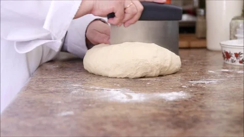Chef cutting fresh bread dough into portions using a bench scraper. Stock Footage 121276129
