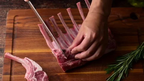 Chef cutting fresh lamb chop on wooden cutting board Stock-Footage 270804625