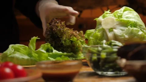 The chef cutting fresh lettuce leaves with a knife on wooden cutting board Stock Footage