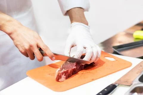 Chef cutting fresh raw meat with knife in the kitchen, Chef cutting beef on.. Fotos de archivo
