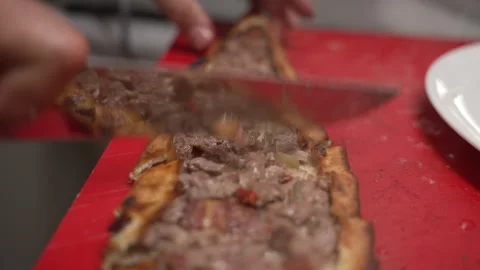 Chef cutting a freshly baked Turkish pide on a red cutting board in a restaurant 動画素材 336741261