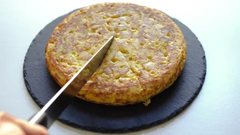 A chef cutting a freshly made Spanish omelette (tortilla de patatas) on a plate Stock Footage 318850463